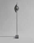 Modern floor lamp with concrete base and metallic shade on a gray background