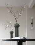 Drop Wall Light Bulp Grey by 101 Copenhagen along with 2 sculptural vases styled with flowers - available at Spacio retail stores in Mumbai & Kolkata.