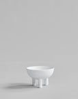 White ceramic bowl on a stand against a light gray background from 101 Copenhagen at Spacio retail stores in Mumbai & Kolkata.