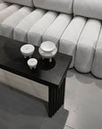 Black coffee table with white ceramic bowls and duck jars in front of a gray textured sofa from 101 Copenhagen at Spacio retail stores in Mumbai & Kolkata.