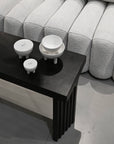 Black coffee table with white ceramic bowls and duck jars in front of a gray textured sofa from 101 Copenhagen at Spacio retail stores in Mumbai & Kolkata.