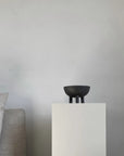 Coffee colour ceramic bowl on a white pedestal against a gray background from 101 Copenhagen at Spacio retail stores in Mumbai & Kolkata.