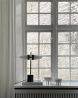 Modern interior with a lamp and decorative bowls on a windowsill with a brick wall view.