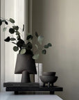 Decorative setup with a black vase, books, and bowls on a shelf against a neutral wall from 101 Copenhagen at Spacio retail stores in Mumbai & Kolkata.