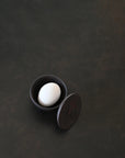 White egg in a coffee colour ceramic container on a dark surface from 101 Copenhagen at Spacio retail stores in Mumbai & Kolkata.