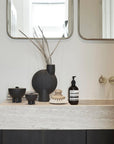 Bathroom vanity with decorative items including a black vase and bottles from 101 Copenhagen at Spacio retail stores in Mumbai & Kolkata.