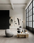 Modern living room with gray chairs, a wooden coffee table, and abstract art on a white wall.
