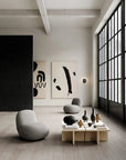 Modern living room with gray chairs, a wooden coffee table, and abstract art on a white wall.