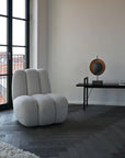 Modern gray armchair in a room with a window and decorative items on a table.