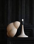 Modern white lamp with a black base against a dark paneled wall