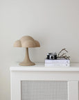 Beige cloud-shaped lamp on a white cabinet against a light gray wall