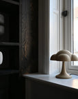 Decorative cloud-shaped lamp on a windowsill with a dark shelf in the background