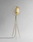 Brass floor lamp with a white shade on a gray background
