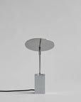 Modern table lamp with round shade and rectangular base on a gray background