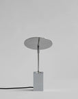 Modern table lamp with round shade and rectangular base on a gray background