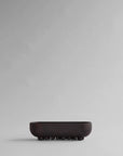 Black ceramic bowl on a gray background from 101 Copenhagen at Spacio retail stores in Mumbai & Kolkata.