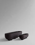 Two black ceramic planters on a gray background from 101 Copenhagen at Spacio retail stores in Mumbai & Kolkata.