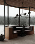 Modern interior with a round dining table and bench seating by large windows with a view of water and trees.