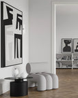 Modern interior with a gray armchair, black side table, and abstract wall art.