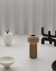 Set of modern vases on a white surface with a white curtain background