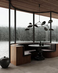 Modern interior with a round dining table and bench seating by large windows with a view of water and trees.