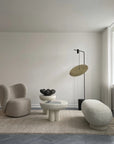 Modern living room with a minimalistic design featuring a chair, ottoman, and floor lamp.