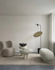 Modern living room with a minimalistic design featuring a chair, ottoman, and floor lamp.