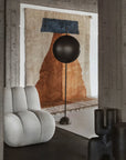 Modern interior with a gray armchair, black floor lamp, and abstract wall art.