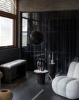 Modern interior with a white armchair, black wall, and decorative elements.