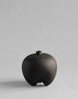 Black ceramic vase on a gray background from 101 Copenhagen at Spacio retail stores in Mumbai & Kolkata.