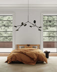 Modern bedroom with a bed, chandelier, and large windows.