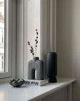 A window sill adorned with a 101Cph Cobra Tall Mini Dark Grey 211034 vase, displaying a beautiful flower.