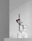 The Double Mini Bubble White Vase from 101cph with decorative flowers and foliage