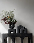 Two 101 Copenhagen Cobra Double Mini Coffee 212002 vases sit on a table in an interior setting, in front of a white wall.