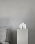 A grey couch with a 101Cph Cobra Uno Mini Bubble White 203021 vase next to it. The 101Cph Cobra Uno Mini Bubble White 203021 vase adds a touch of elegance to the space, perfectly complementing the sleek design of the Cobra Uno Mini Bubble couch by 101 Copenhagen.