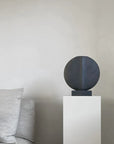 A quirky table lamp on a pedestal next to a couch featuring the 101Cph Guggenheim Mini Coffee 111220 from 101 Copenhagen.