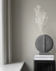 The 101Cph Guggenheim Mini Dark Grey 203005 by 101 Copenhagen sits on a table in front of a window, showcasing the influence of the Cobra Arts Movement.