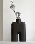 Black abstract vase with dried flowers on a white surface from 101 Copenhagen at Spacio retail stores in Mumbai & Kolkata.