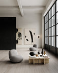 Modern living room with minimalistic decor, abstract art, and a large window.