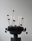 Candle holder with black flowers on a gray background in a ceramic bowl from 101 Copenhagen at Spacio retail stores in Mumbai & Kolkata.