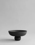 Black ceramic bowl on a light gray background from 101 Copenhagen at Spacio retail stores in Mumbai & Kolkata.