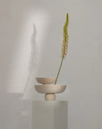 Minimalist ceramic vase with a single green stem on a neutral background from 101 Copenhagen at Spacio retail stores in Mumbai & Kolkata.
