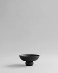 Black ceramic bowl on a light gray background from 101 Copenhagen at Spacio retail stores in Mumbai & Kolkata.