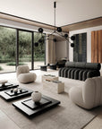 Modern living room with gray sofa, white chairs, and black coffee tables.