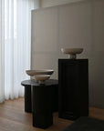 Three ceramic bowls on black pedestals against a neutral wall with white curtains from 101 Copenhagen at Spacio retail stores in Mumbai & Kolkata.