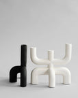 Two modern candle holders, one black and one white, on a light gray background from 101 Copenhagen at Spacio retail stores in Mumbai & Kolkata.