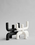 Two modern candle holders, one black and one white, on a light gray background from 101 Copenhagen at Spacio retail stores in Mumbai & Kolkata.