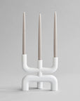 White candle holder with three candles on a gray background from 101 Copenhagen at Spacio retail stores in Mumbai & Kolkata.