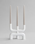 White candle holder with three candles on a gray background from 101 Copenhagen at Spacio retail stores in Mumbai & Kolkata.