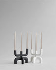 Two modern candle holders with candles on a gray background from 101 Copenhagen at Spacio retail stores in Mumbai & Kolkata.